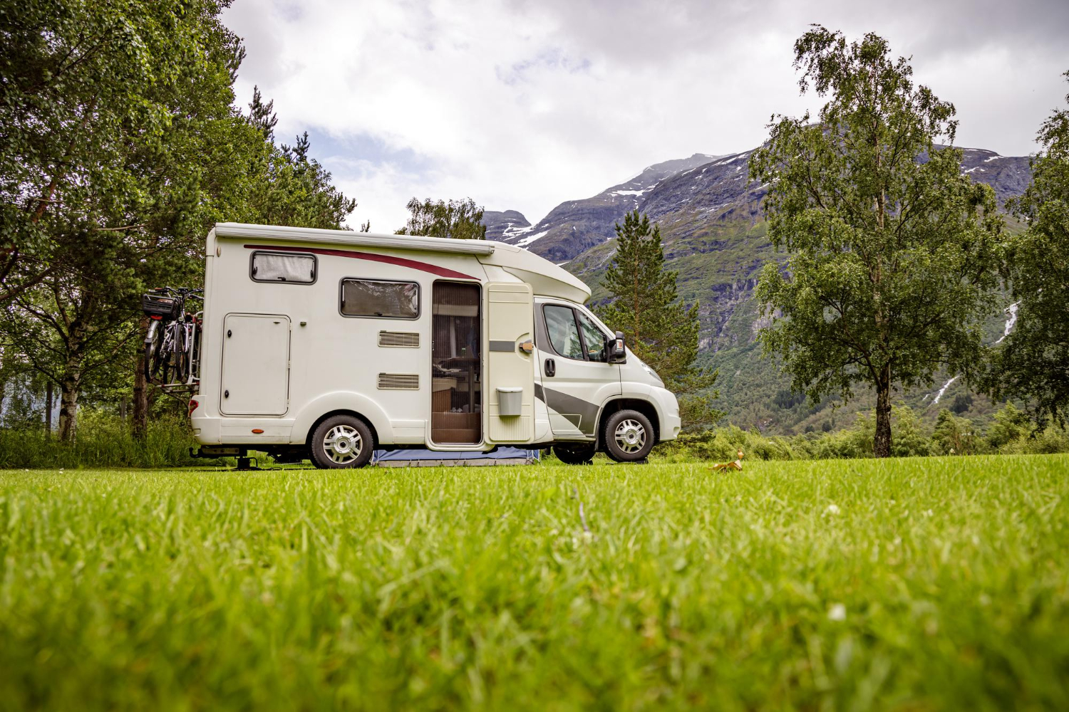 Camping car garé sur un espace verdoyant face aux montagnes